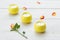 Three yellow scented candles on a wooden table. Rose petals are scattered on the table surface