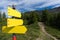 three yellow signposts narrow footpath alpine terrain