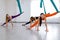 Three yogi women makes side splits using blue hammock for aerial fly yoga. Concept wellness yoga, group training.