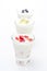 Three yogurt with fruit in a glass beaker on a white background