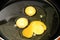 Three yolks from eggs in a frying pan in oil