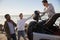 Three young adult male friends unloading backpacks from jeep