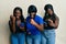 Three young african american friends using smartphone angry and mad raising fist frustrated and furious while shouting with anger