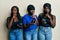 Three young african american friends using smartphone asking to be quiet with finger on lips