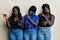 Three young african american friends using smartphone pointing aside worried and nervous with forefinger, concerned and surprised