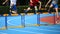 Three young athletes while running hurdles on the running track