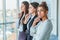 Three young beautiful brunette business ladies in the office. All serious, folded hands look to the side with