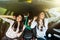 Three young beauty girls driving in a car dancing and having fun in city street