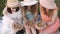 Three young best friends sitting on the grass and holding wooden plates with tasty french food