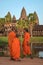 Three young buddhist monks at Angkor Wat, Cambodia, in traditional saffron robes, contemplating the majestic temple.