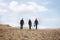 Three young business people walking through the desert, rear view, distant