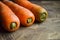 Three young carrots lie on a wooden cutting board. Fresh carrots on a wooden table. Harvest from the garden. Vegetables Vitamins