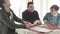 Three young Caucasian men sitting at the table, talking and laughing. Male university students studying together indoors