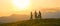 Three young cyclists rest at the mountain top before riding downhill at sunset.