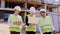 Three young diverse specialists of construction walking in front of the camera through the construction site and