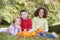 Three young friends sitting on grass with pumpkins