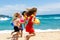 Three young girlfriends running on beach.