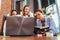 Three young girlfriends talking online lesson using a laptop sitting in a library