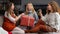 Three young girls sitting on the couch and having fun unwrapping Christmas presents at home