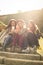 Three young girls sitting on the stairs at the public park. Three best friends sitting on stairs and using smart phone.