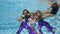 Three young girls, synchronized swimmers, in beautiful swimsuits dive under the water in an outdoor pool on a summer day