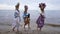 Three young gorgeous Ukrainian women in traditional dresses and head wreathes walking along sandy river beach. Smiling