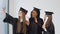 Three young happy students women of different nationalities stand together side by side and take a selfie with diplomas