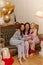 Three young interracial ladies laughing looking at camera sitting on couch hugging at pajama party.