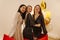 Three young interracial ladies smiling while looking at camera at party in elegant outfit indoors.