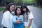 Three young latin female friends walking at the woods. Embrace each other and laughing. Friends making selfie.