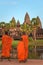 Three young monks at Angkor Wat, in traditional saffron colored robes, admiring the majestic temple.