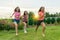 Three young sports girls teenagers running on a green lawn against the backdrop of summer sunset.