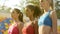 Three young sportswomen standing in one line, attentively listening to coach