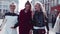 Three young stylish women walking, talking, laughing in the city-center. Fashionable look, amazing red coat. True