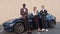Three young successful people on the background of a sports electric car, use gadgets phone and tablet. technology and