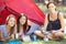 Three Young Women Cooking On Camping Stove Outside Tent