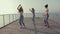 Three young women dancing twerk on a wooden pier near the sea