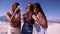 Three young women friends having drinks at the beach