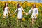 Three young women in white dress posing against the blue sky in sunflowers field