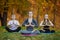 Three young yoga practitioners doing yoga exercises in park. Women meditate outdoor infront of beautiful autumn nature