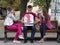 Three youngsters, teenagers, one caucasian male and two females, eating pizza and smiling sitting on a bench in downtown Lviv