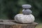 Three zen stones pile on wooden stump, white and grey meditation pebbles tower