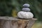 Three zen stones pile on wooden stump, white and grey meditation pebbles tower