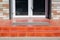 Threshold with a paved red tile and a foot mat at the front door.