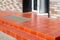 Threshold with a paved red tile and a foot mat at the open front door.