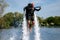 Thrillseeker, water sports lover, athlete strapped to Jet Lev, levitation hovers over lake with blue sky and trees