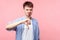 Thumb down, I don`t like it. Portrait of upset displeased brown-haired man showing dislike gesture. isolated on pink background