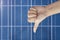 Thumb down on a solar panels background. Photovoltatic power industry.