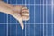 Thumb down on a solar panels background. Photovoltatic power industry.