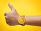 Thumb up Hand Wearing Fruit Orange Watch on Yellow Background